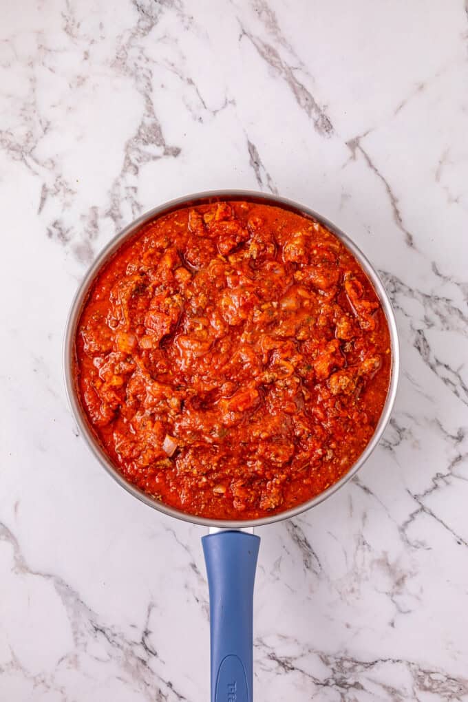 Ground beef with pasta sauce, frozen ravioli, and shredded cheese are layered to make this Crockpot Ravioli Lasagna. Meat sauce in a pan
