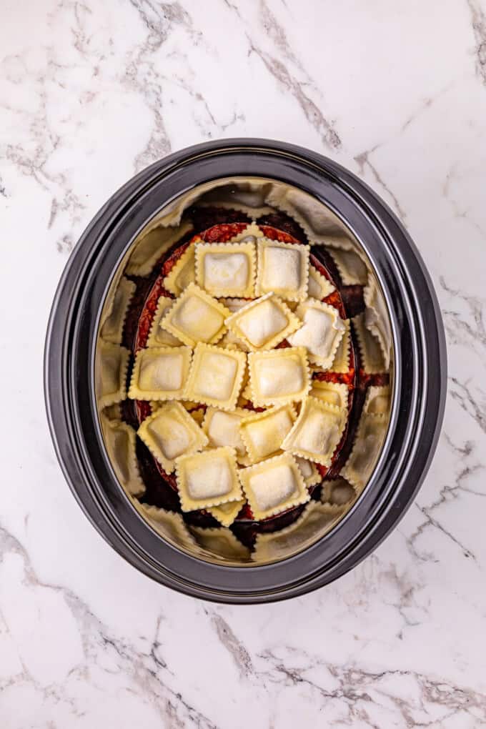 Ground beef with pasta sauce, frozen ravioli, and shredded cheese are layered to make this Crockpot Ravioli Lasagna. Frozen ravioli on top of sauce in the crockpot