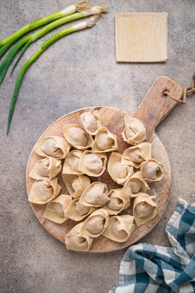 With a savory ground pork filling and crispy golden outside, this Fried Wonton recipe brings Chinese takeout to the table in 30 minutes. Uncooked pork wontons on a wooden platter