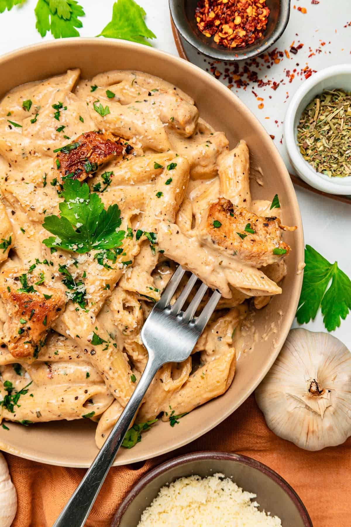 With tender, juicy chicken coated in a creamy garlic sauce, this Garlic Parmesan Chicken Pasta is an easy weeknight dinner. A fork resting on a bowl of garlic parmesan chicken pasta