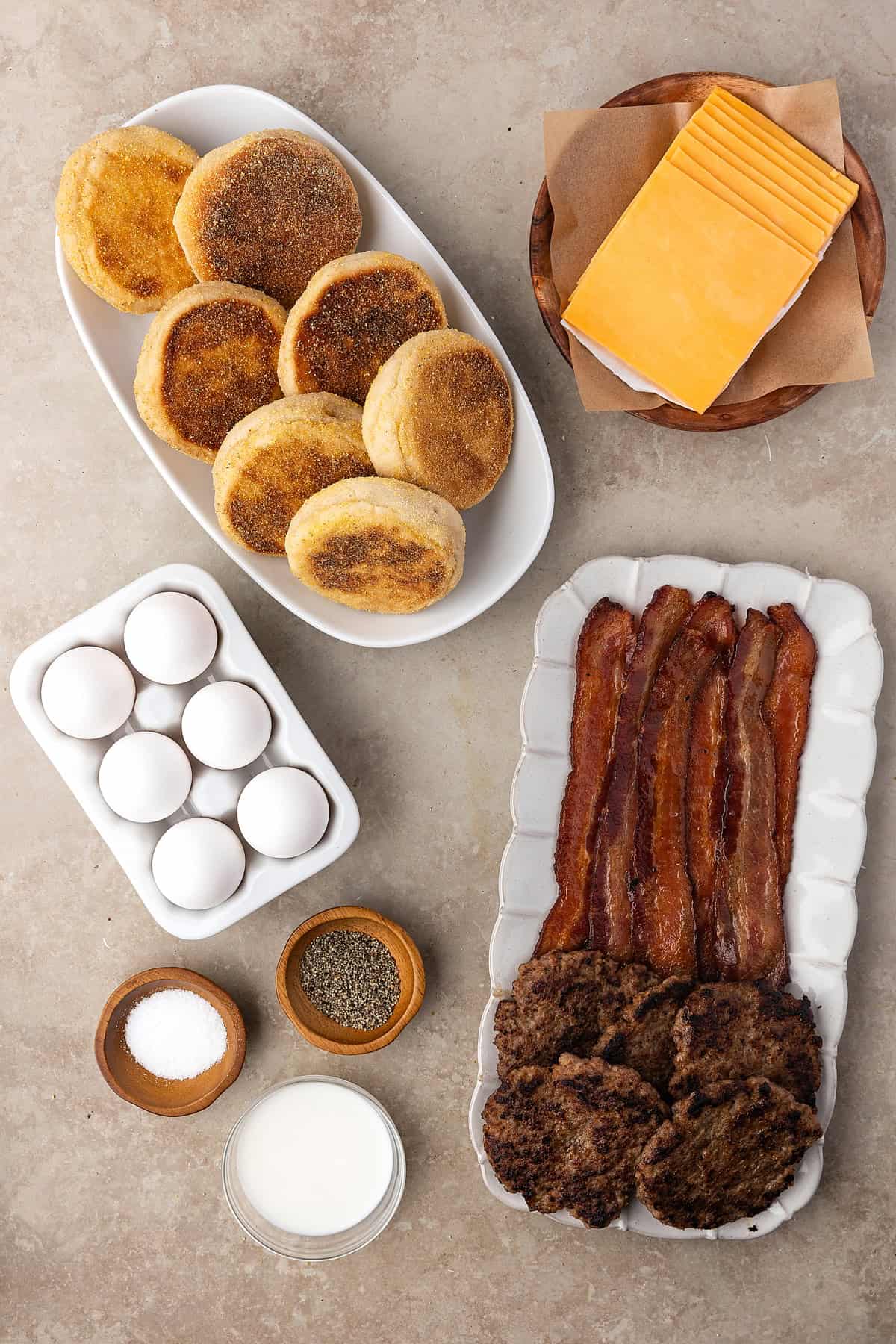 Made with English muffins, sheet pan eggs, cheese, and meat, these Make Ahead Breakfast Sandwiches are perfect for busy mornings! Overhead view of ingredients needed to make English muffin breakfast sandwiches