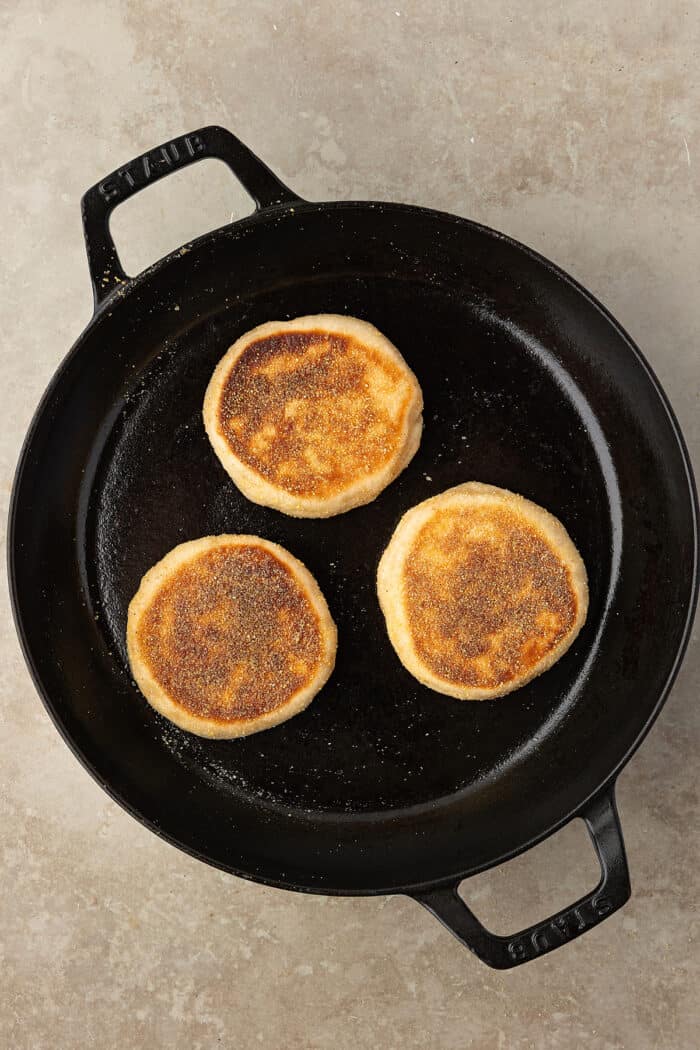 These Sourdough English Muffins are soft, chewy, and full of the classic nooks and crannies everyone loves. Sourdough English muffins in a cast iron skillet
