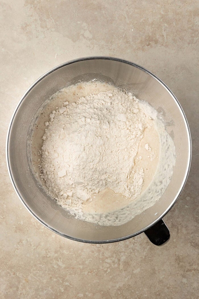 These Sourdough English Muffins are soft, chewy, and full of the classic nooks and crannies everyone loves. Flour added to yeast in a bowl