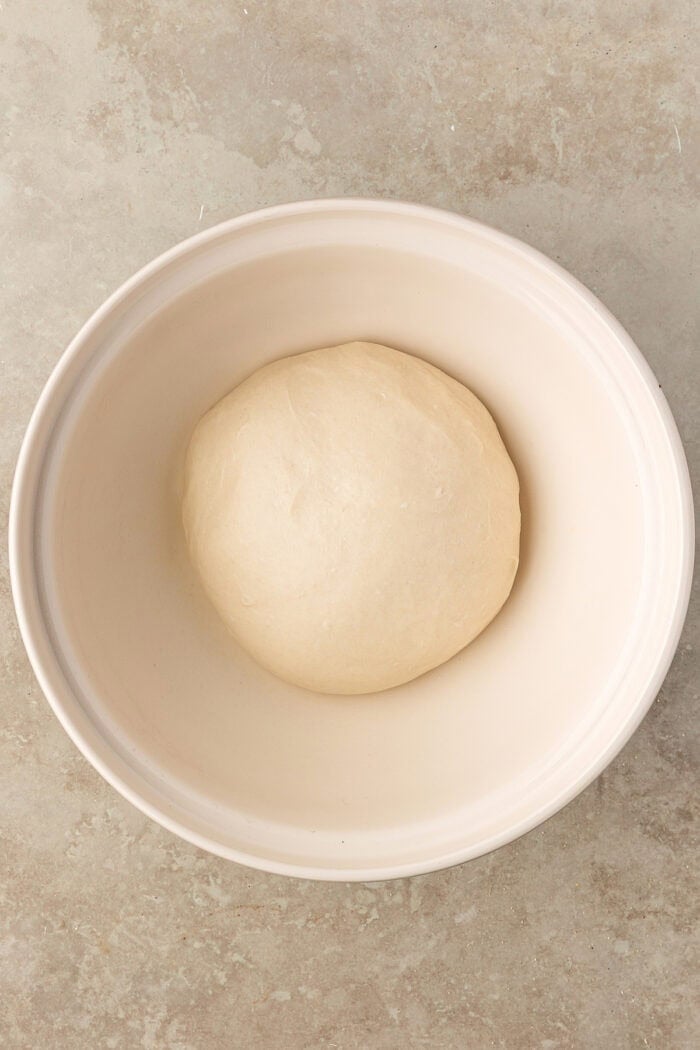 These Sourdough English Muffins are soft, chewy, and full of the classic nooks and crannies everyone loves. A ball of dough before it has risen in a bowl