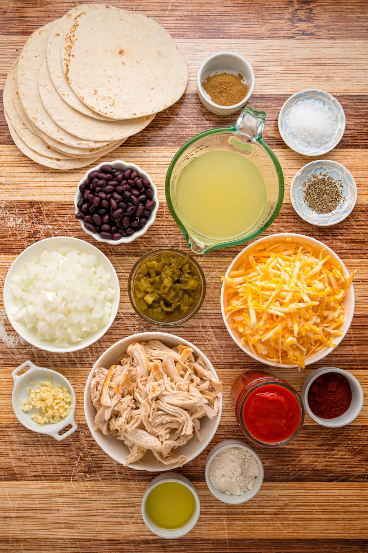 With layers of tortillas, enchilada sauce, gooey cheese, and chicken and beans, Chicken Enchilada Casserole is an easy weeknight dinner. Overhead view of ingredients in chicken enchilada casserole