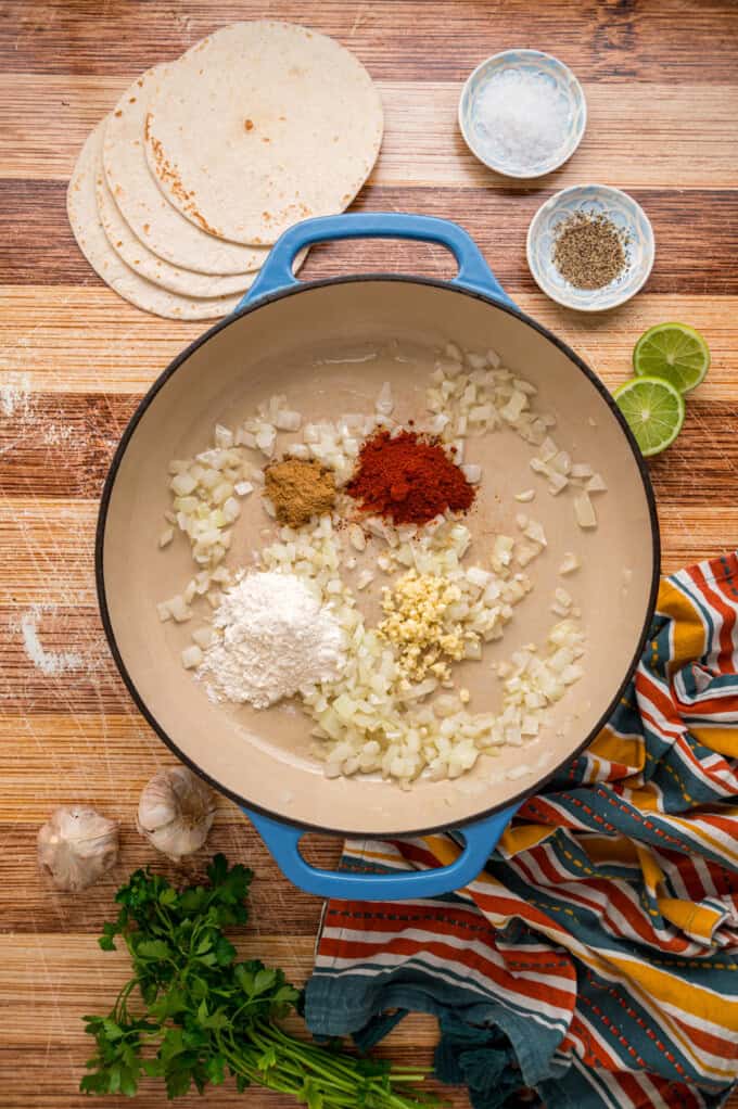 With layers of tortillas, enchilada sauce, gooey cheese, and chicken and beans, Chicken Enchilada Casserole is an easy weeknight dinner. Spices, garlic, and flour added to sauteed onions