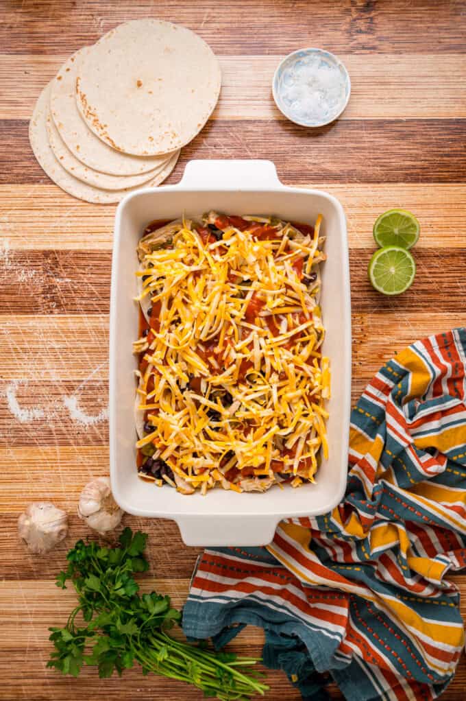 With layers of tortillas, enchilada sauce, gooey cheese, and chicken and beans, Chicken Enchilada Casserole is an easy weeknight dinner. Enchilada sauce and shredded cheese on top of chicken filling