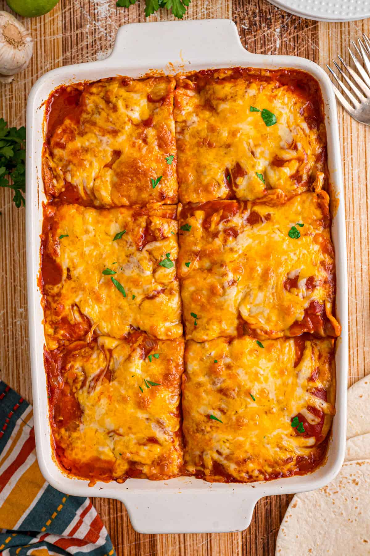 With layers of tortillas, enchilada sauce, gooey cheese, and chicken and beans, Chicken Enchilada Casserole is an easy weeknight dinner. chicken enchilada casserole cut into squares.