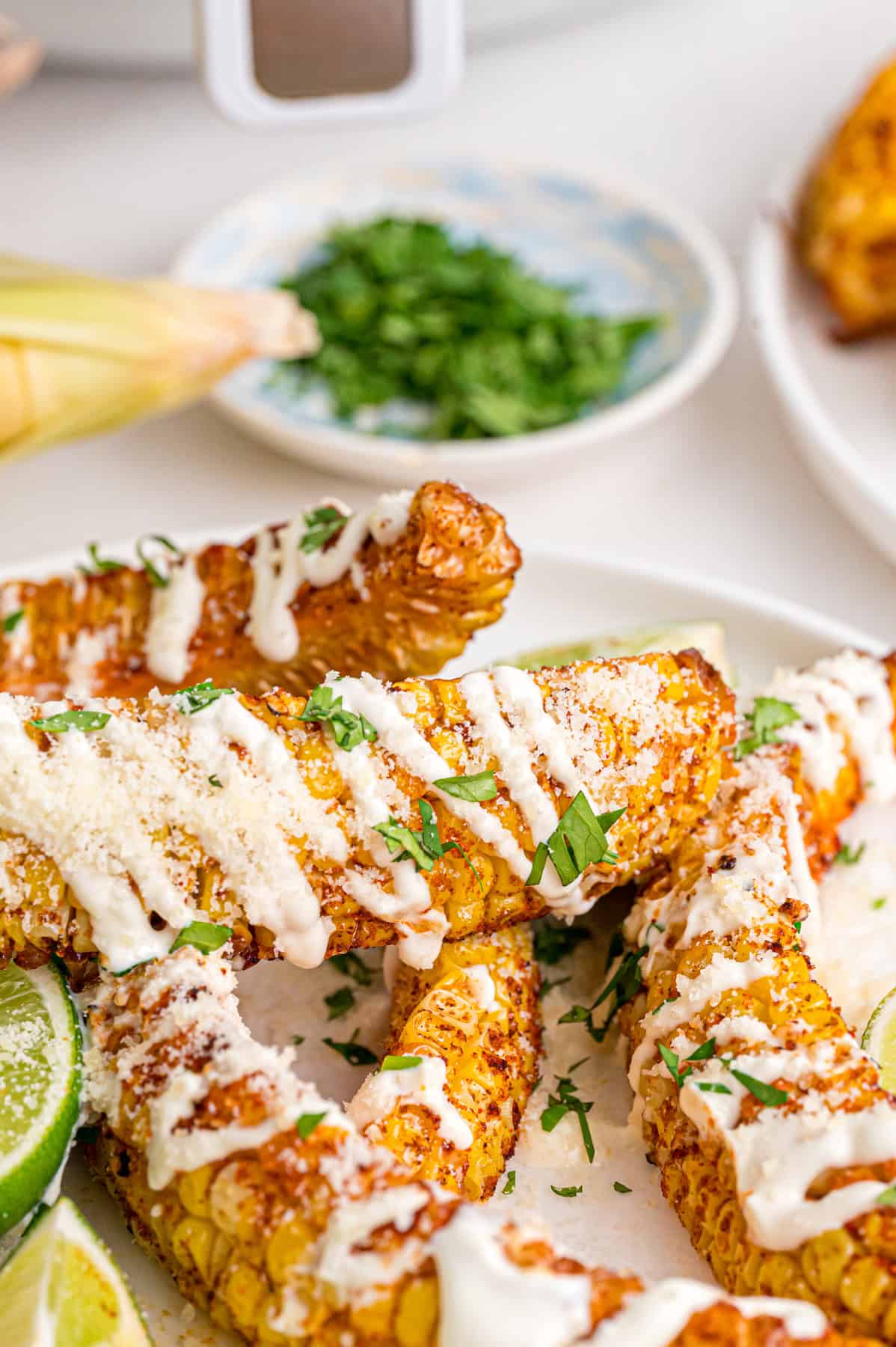 These easy Corn Ribs are coated in warm, smoky spices, cooked in the air fryer or grill, drizzled with lime crema. Corn ribs on a plate drizzled with lime crema