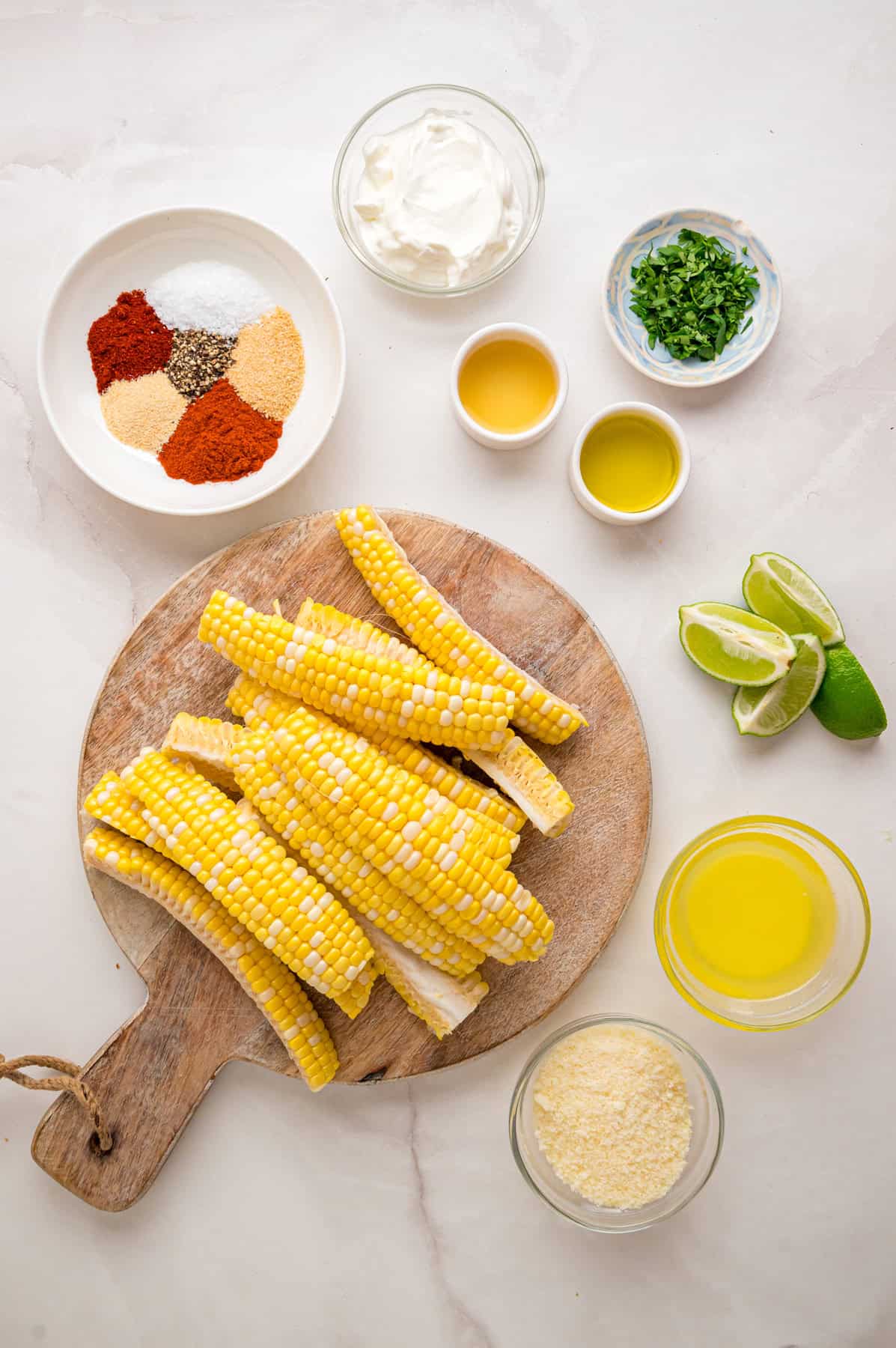 These easy Corn Ribs are coated in warm, smoky spices, cooked in the air fryer or grill, drizzled with lime crema. Overhead view of ingredients needed to make corn ribs