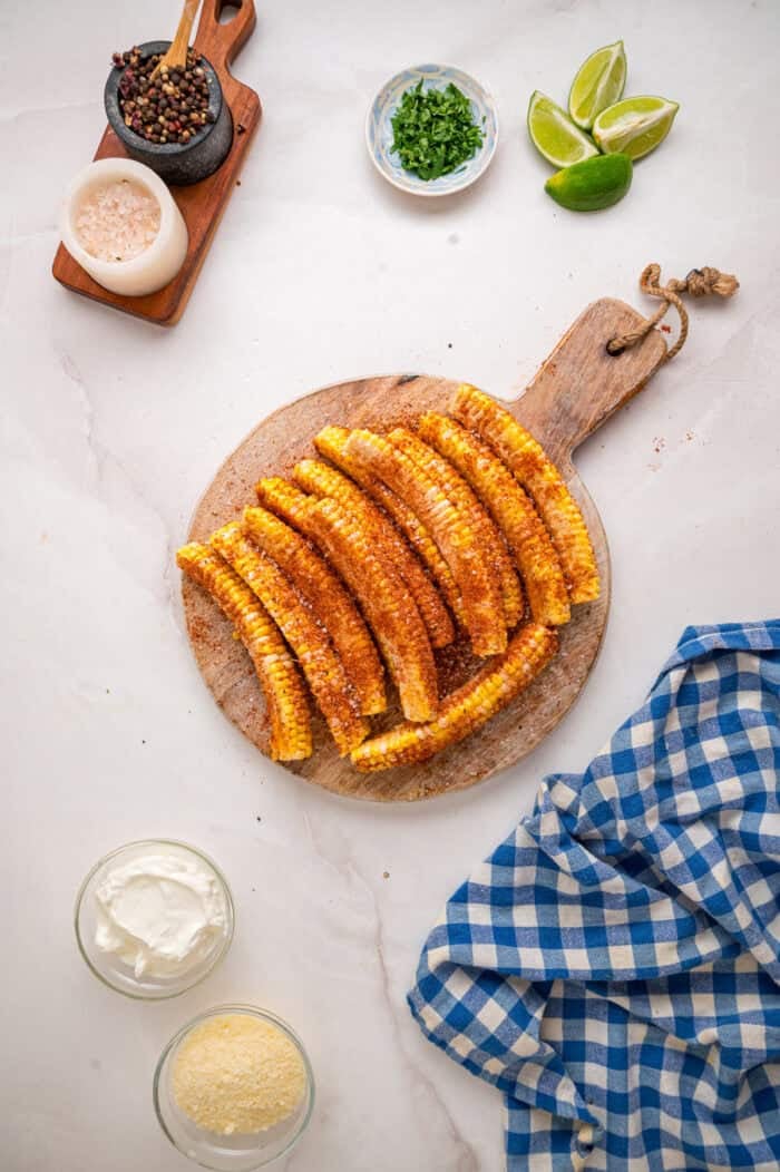 These easy Corn Ribs are coated in warm, smoky spices, cooked in the air fryer or grill, drizzled with lime crema. Seasoned corn ribs on a cutting board