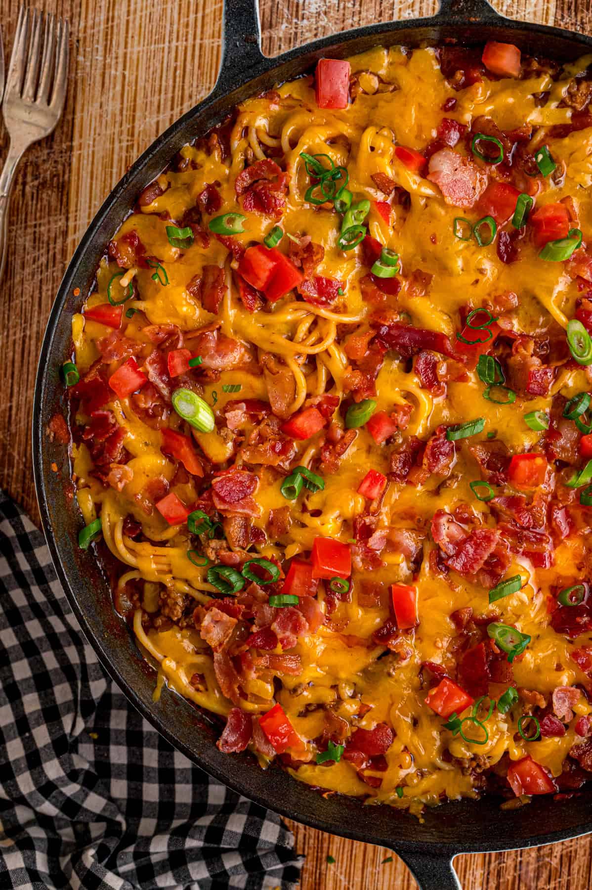 Cowboy Spaghetti is an extra hearty and flavorful take on classic spaghetti, with ground beef, bacon, tomatoes and green chilies, and cheese. Overhead view of a skillet of cowboy spaghetti