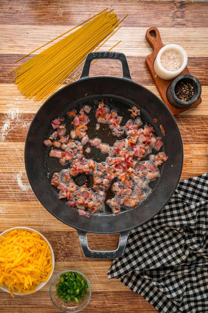 Cowboy Spaghetti is an extra hearty and flavorful take on classic spaghetti, with ground beef, bacon, tomatoes and green chilies, and cheese. Diced bacon in a skillet