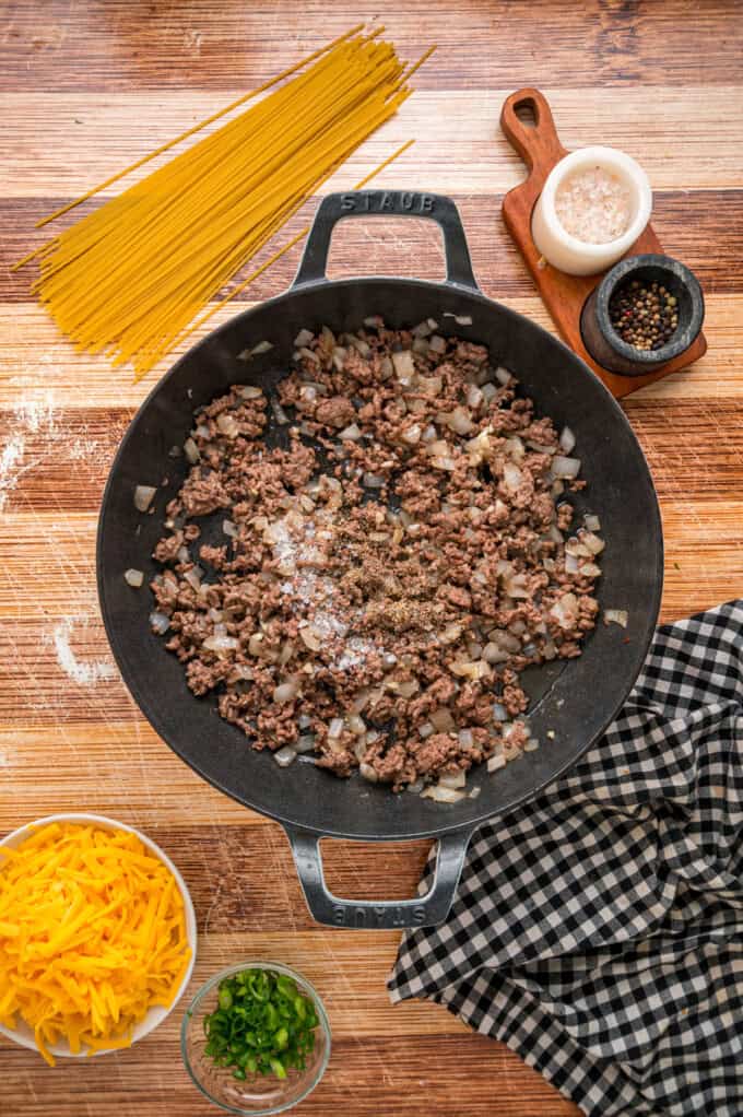 Cowboy Spaghetti is an extra hearty and flavorful take on classic spaghetti, with ground beef, bacon, tomatoes and green chilies, and cheese. Ground beef and onions in a skillet