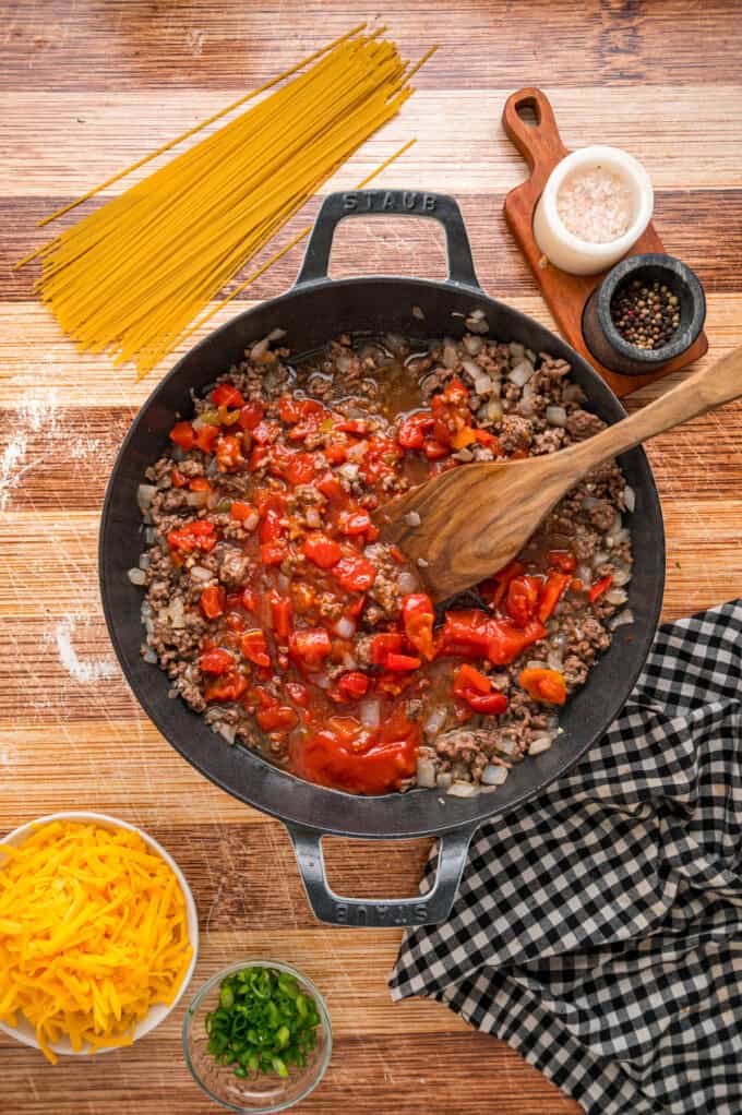 Cowboy Spaghetti is an extra hearty and flavorful take on classic spaghetti, with ground beef, bacon, tomatoes and green chilies, and cheese. Stirring diced tomatoes into ground beef