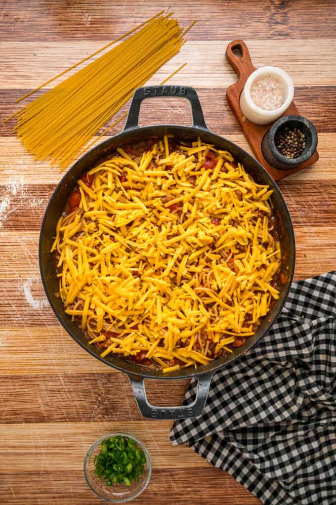 Cowboy Spaghetti is an extra hearty and flavorful take on classic spaghetti, with ground beef, bacon, tomatoes and green chilies, and cheese. Shredded cheddar cheese sprinkled on the skillet