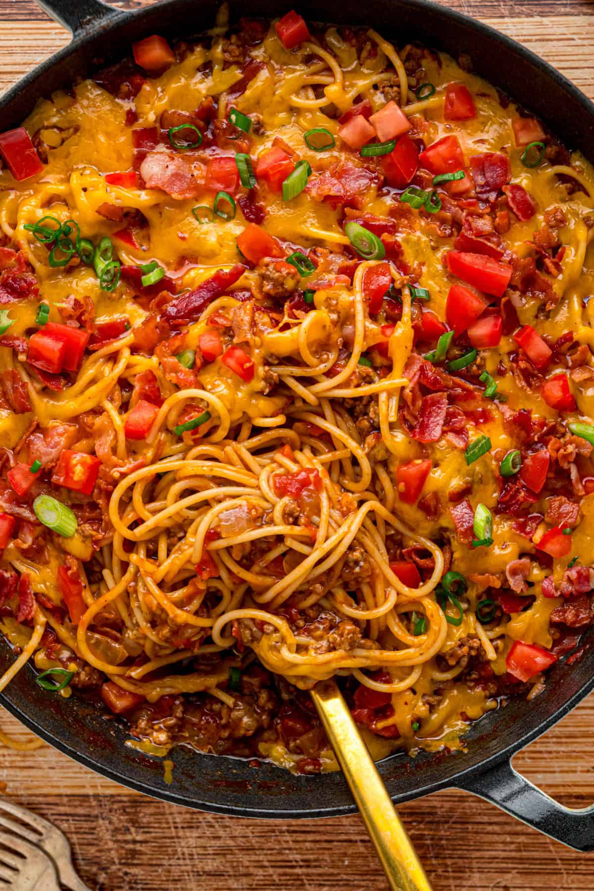 Cowboy Spaghetti is an extra hearty and flavorful take on classic spaghetti, with ground beef, bacon, tomatoes and green chilies, and cheese. Cowboy Spaghetti in a skillet with a spoon