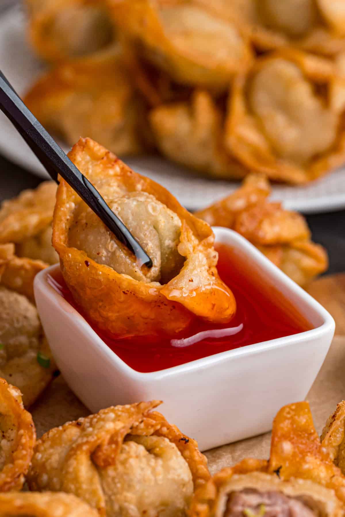 With a savory ground pork filling and crispy golden outside, this Fried Wonton recipe brings Chinese takeout to the table in 30 minutes. A fried wonton being dipped into sweet and sour sauce.