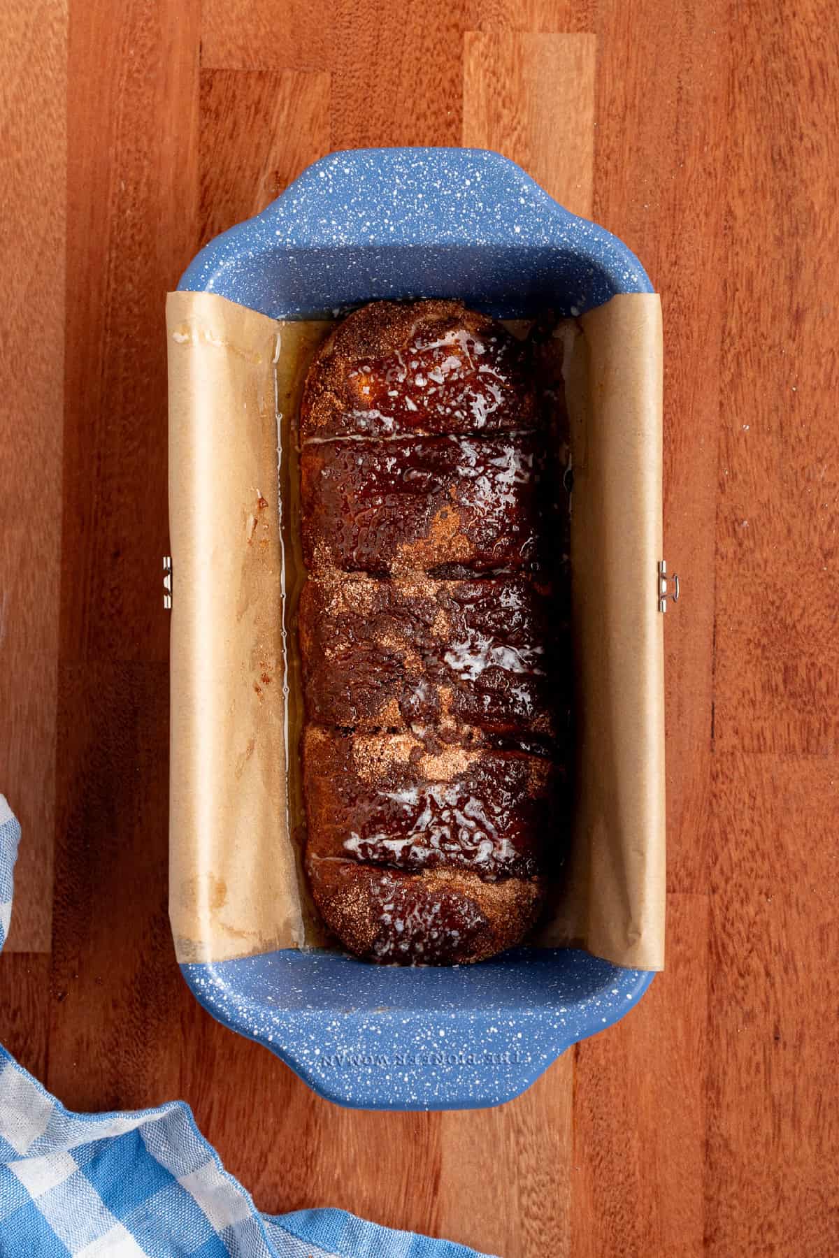 This Dollywood Cinnamon Bread copycat recipe has a buttery, caramelized cinnamon-sugar coating and sweet glaze drizzled over the top. bread dough covered in cinnamon sugar and butter ready to be baked