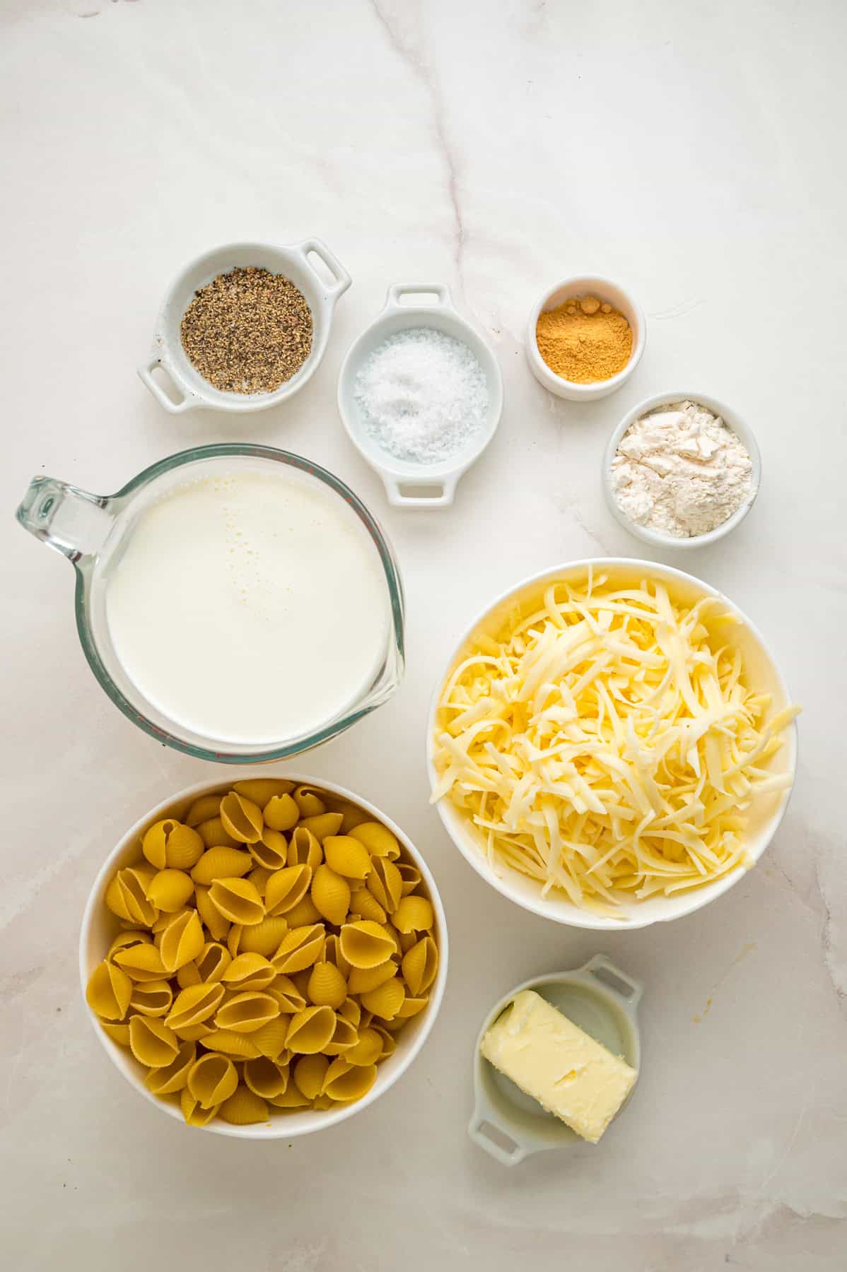 Tender shell pasta is coated in a thick, creamy white cheddar cheese sauce in this copycat Panera Mac and Cheese recipe. Overhead view of ingredients needed to make Panera mac and cheese