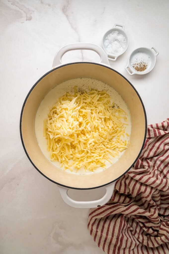 Tender shell pasta is coated in a thick, creamy white cheddar cheese sauce in this copycat Panera Mac and Cheese recipe. Shredded water cheddar added to half and half in a pot