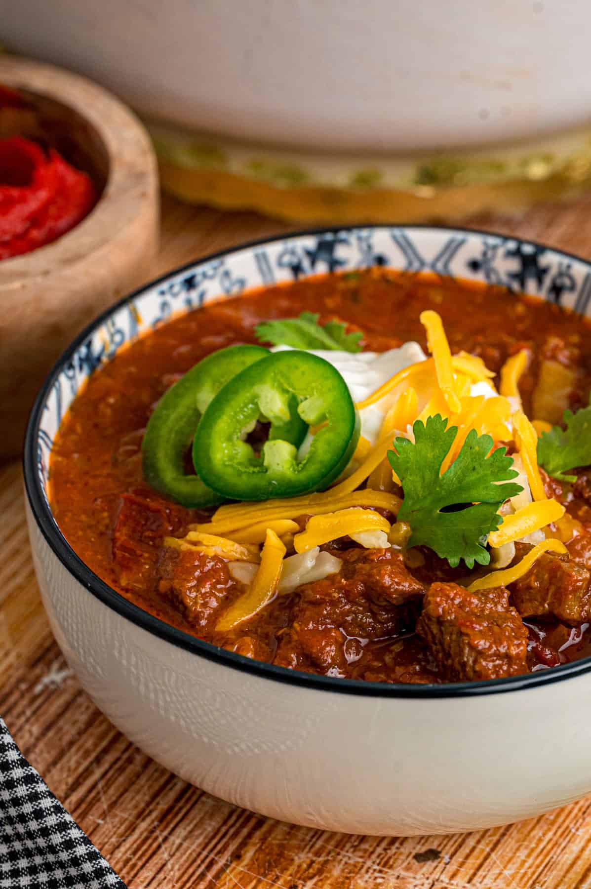 Seared chunks of chuck roast are simmered with crushed tomatoes, jalapenos, and chipotles in adobo sauce to make this Texas Chili recipe. A bowl of Texas chili with toppings