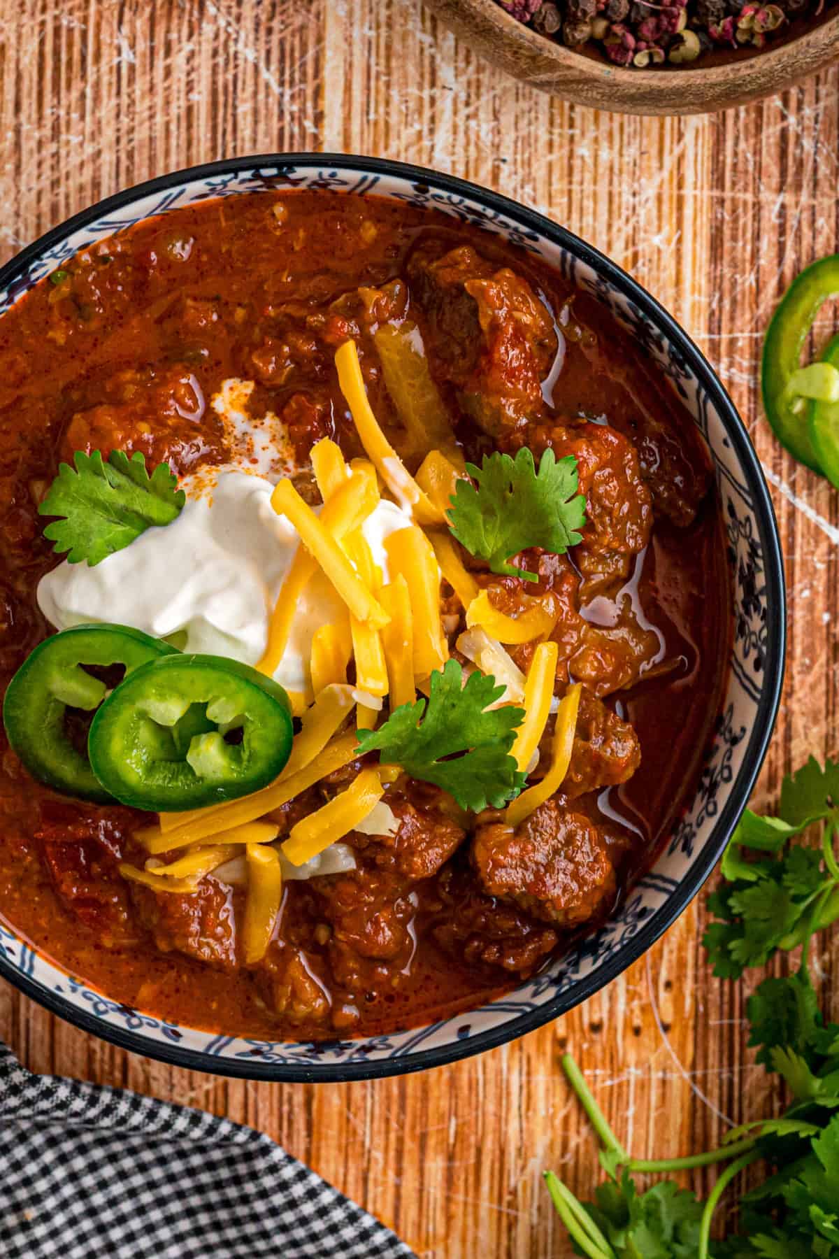 Seared chunks of chuck roast are simmered with crushed tomatoes, jalapenos, and chipotles in adobo sauce to make this Texas Chili recipe. a bowl of Texas chili with toppings.