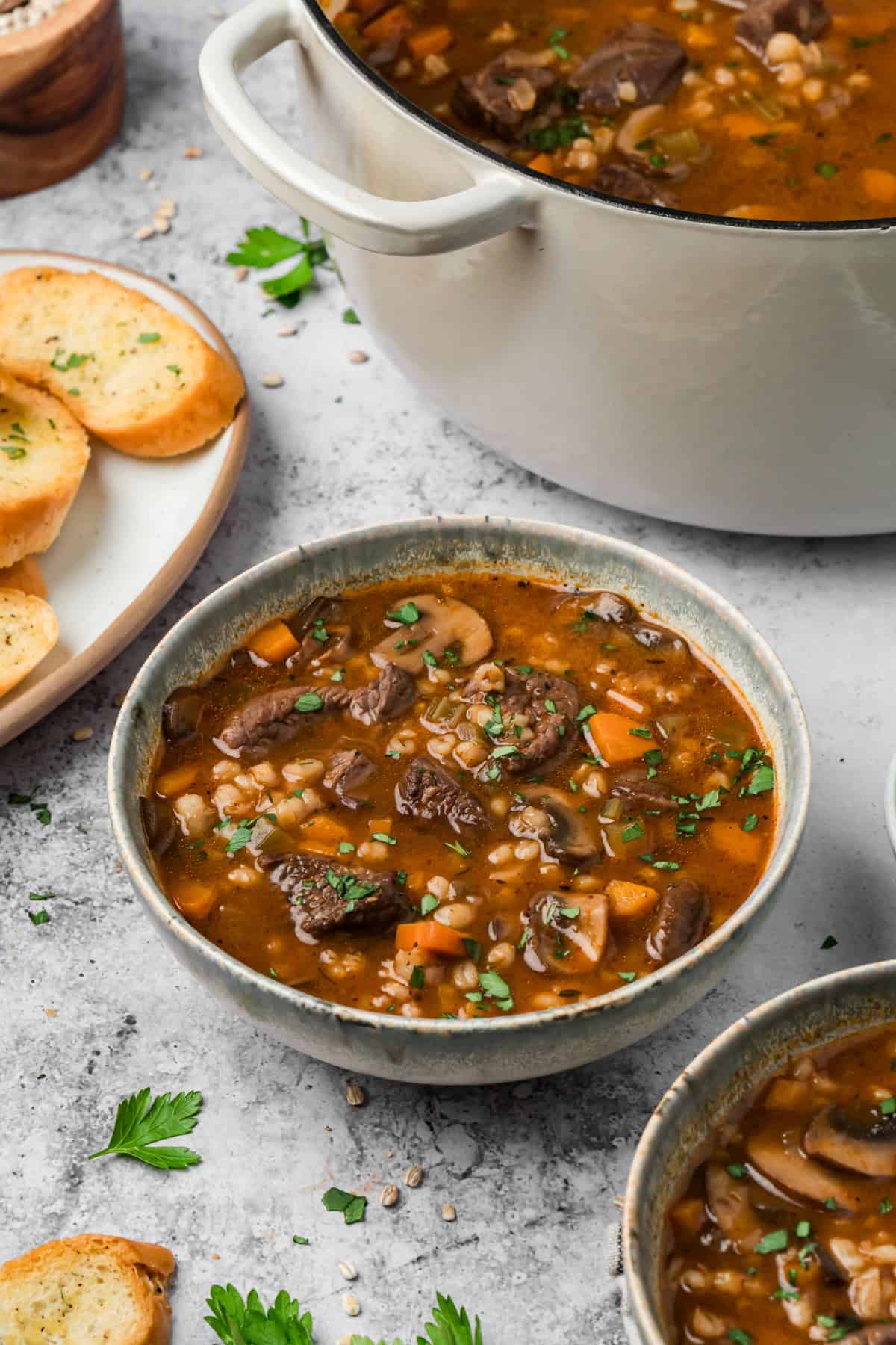 This hearty Beef Barley Mushroom Soup is nourishing, comforting, and perfect for chilly nights, with tender pieces of beef. A bowl of soup in front of a pot