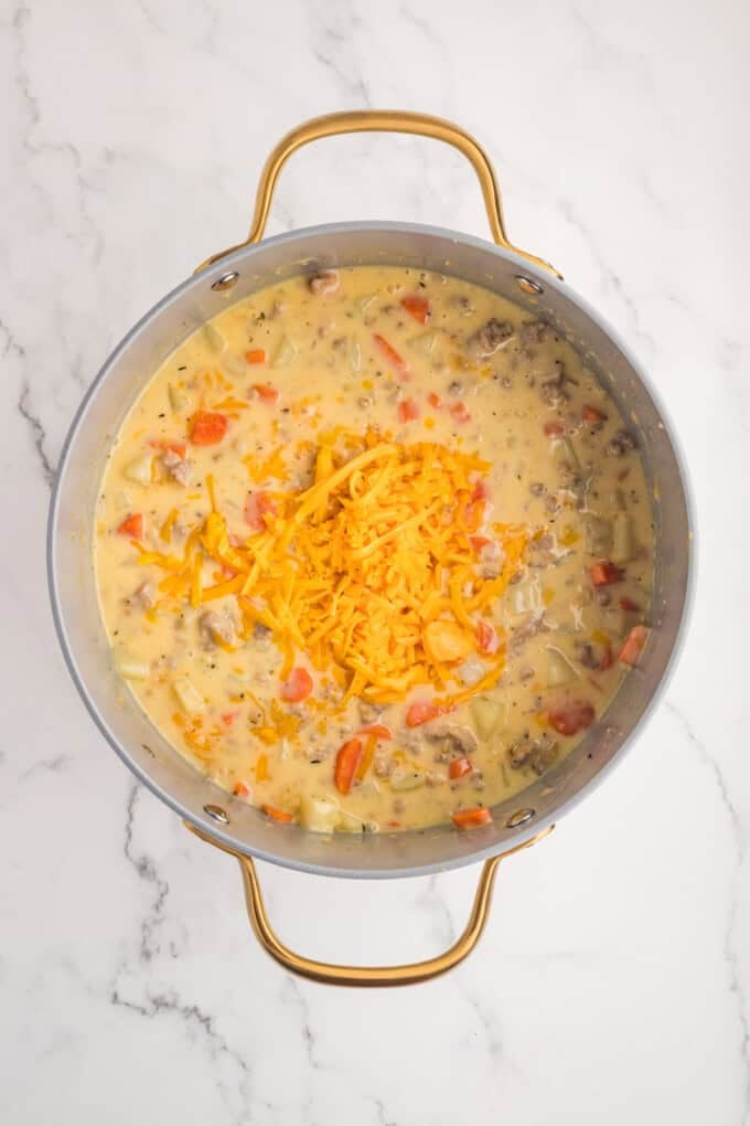 This Sausage Potato Soup is rich, creamy, and loaded with savory Italian sausage, tender potatoes, sweet carrots, and sharp cheddar cheese. Shredded cheese added to sausage potato soup