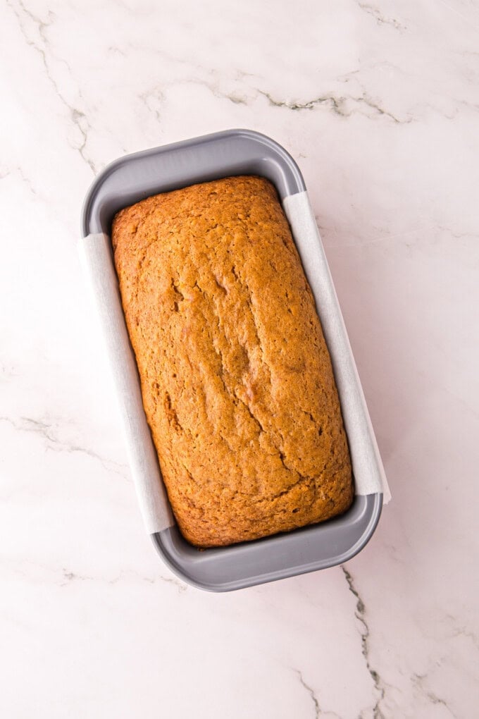 This Sweet Potato Bread is moist, dense, and packed with warm spices. Topped with butter glaze and pecans! Perfect for fall. Overhead view of sweet potato bread in a loaf pan