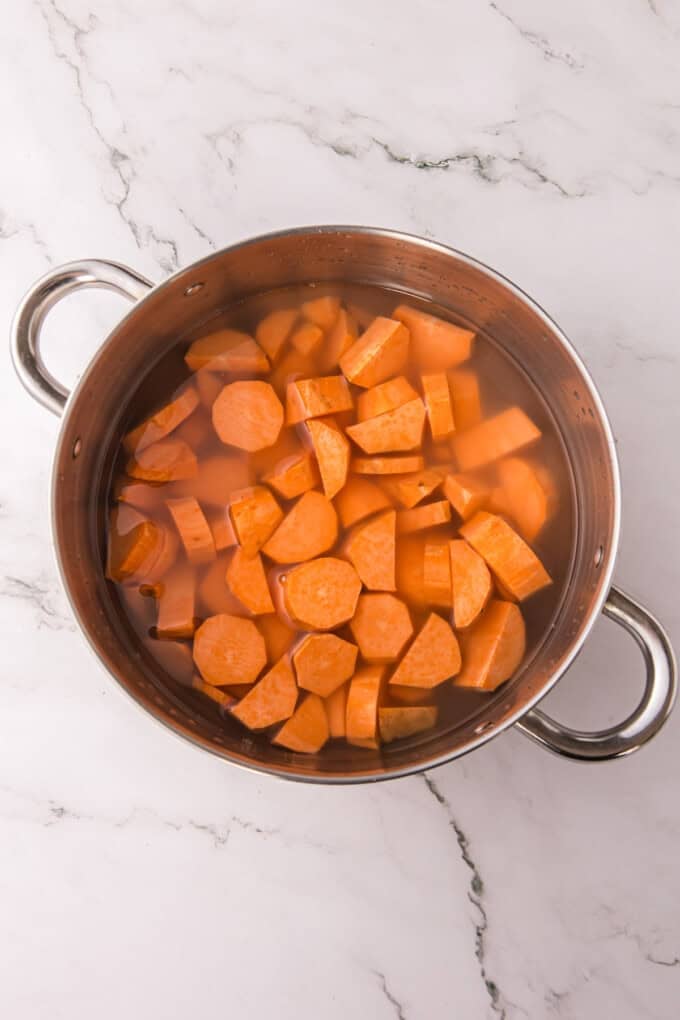 This Sweet Potato Bread is moist, dense, and packed with warm spices. Topped with butter glaze and pecans! Perfect for fall. Sweet potatoes in a pot of water