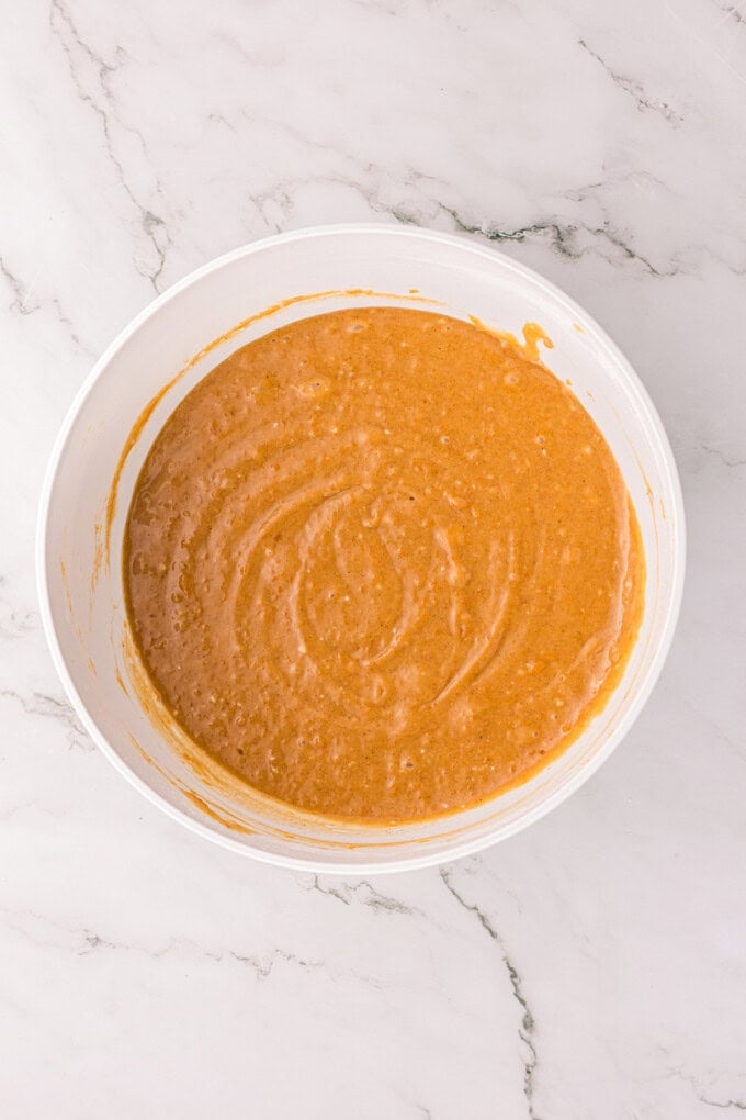 This Sweet Potato Bread is moist, dense, and packed with warm spices. Topped with butter glaze and pecans! Perfect for fall. Sweet potato bread batter in a bowl