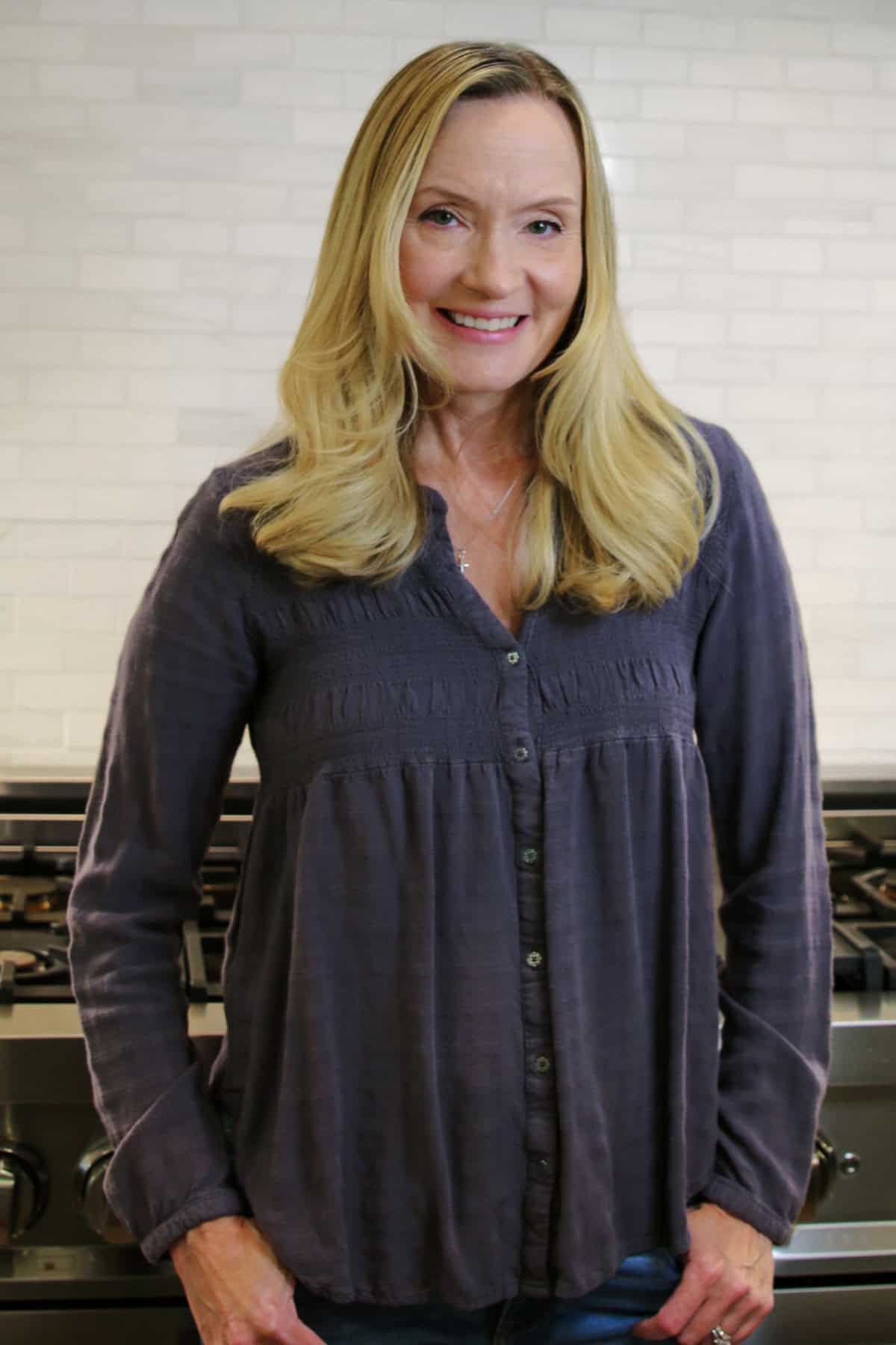 Portrait of Jill standing in her kitchen