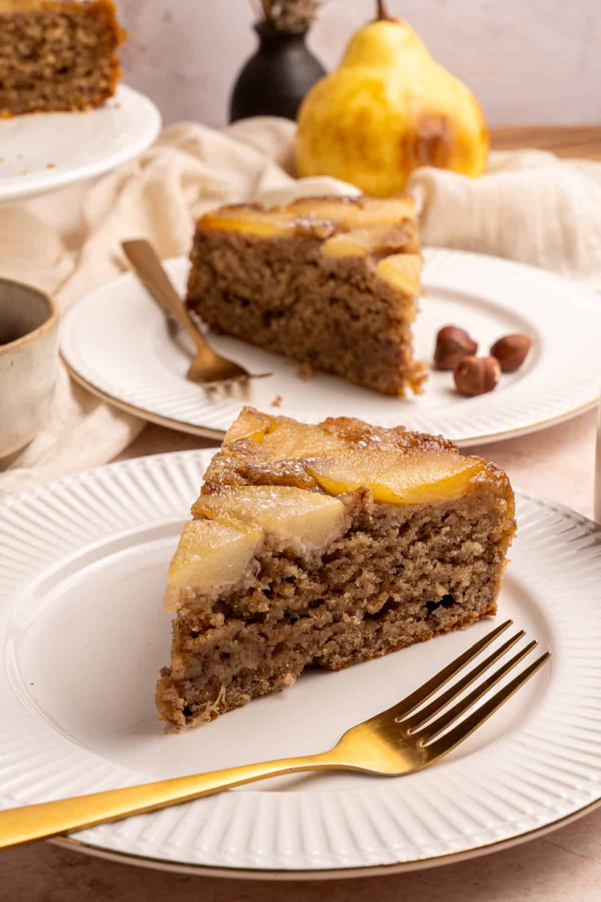 With a moist and tender cake topped with soft caramelized pears, this Pear Upside Down Cake is perfect for fall. Pear Upside Down Cake slices on plates.