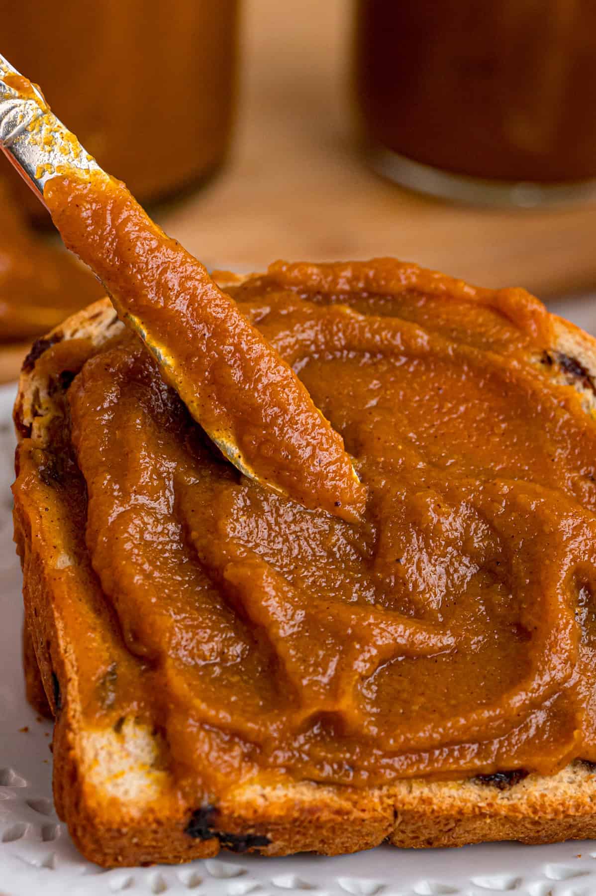 Made with pumpkin puree, brown sugar, maple syrup, and warm spices, you’ll want to spread this Pumpkin Butter on everything. A knife spreading pumpkin butter on toast