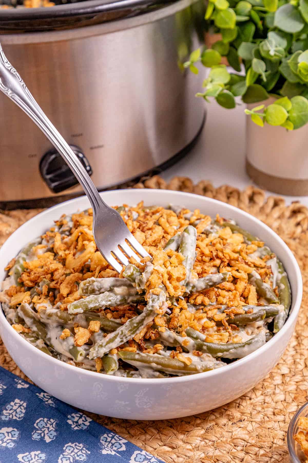 This Slow Cooker Green Bean Casserole is the perfect hands-off side dish for the holidays! Made with just a few ingredients. A fork in a bowl of green bean casserole