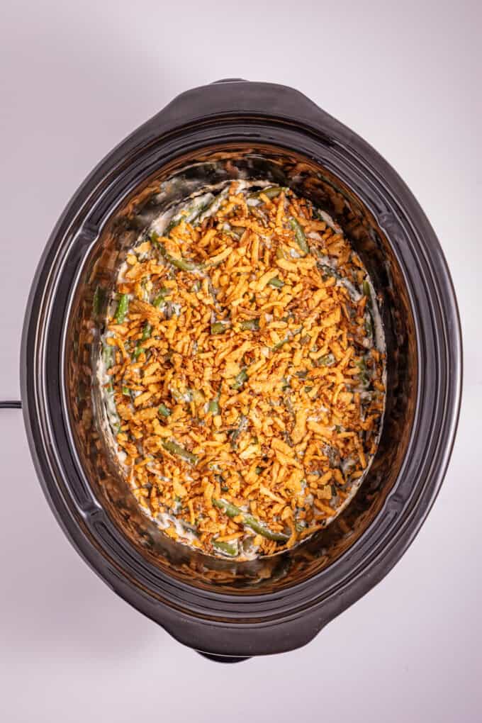 This Slow Cooker Green Bean Casserole is the perfect hands-off side dish for the holidays! Made with just a few ingredients. Green bean casserole topped with fried onions in the slow cooker