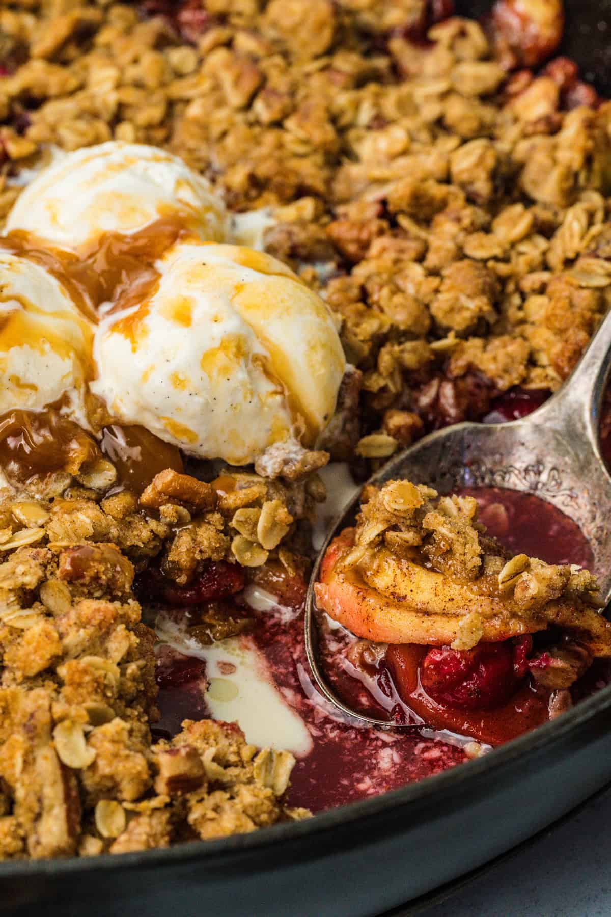 This Apple Cranberry Crisp is baked in a cast-iron skillet, giving the fruit a caramelized edge while the buttery oat turns golden & crunchy. A spoon in a skillet of apple cranberry crisp