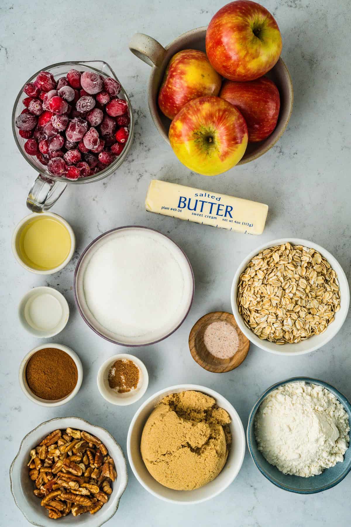 This Apple Cranberry Crisp is baked in a cast-iron skillet, giving the fruit a caramelized edge while the buttery oat turns golden & crunchy. Overhead view of ingredients needed to make apple cranberry crisp