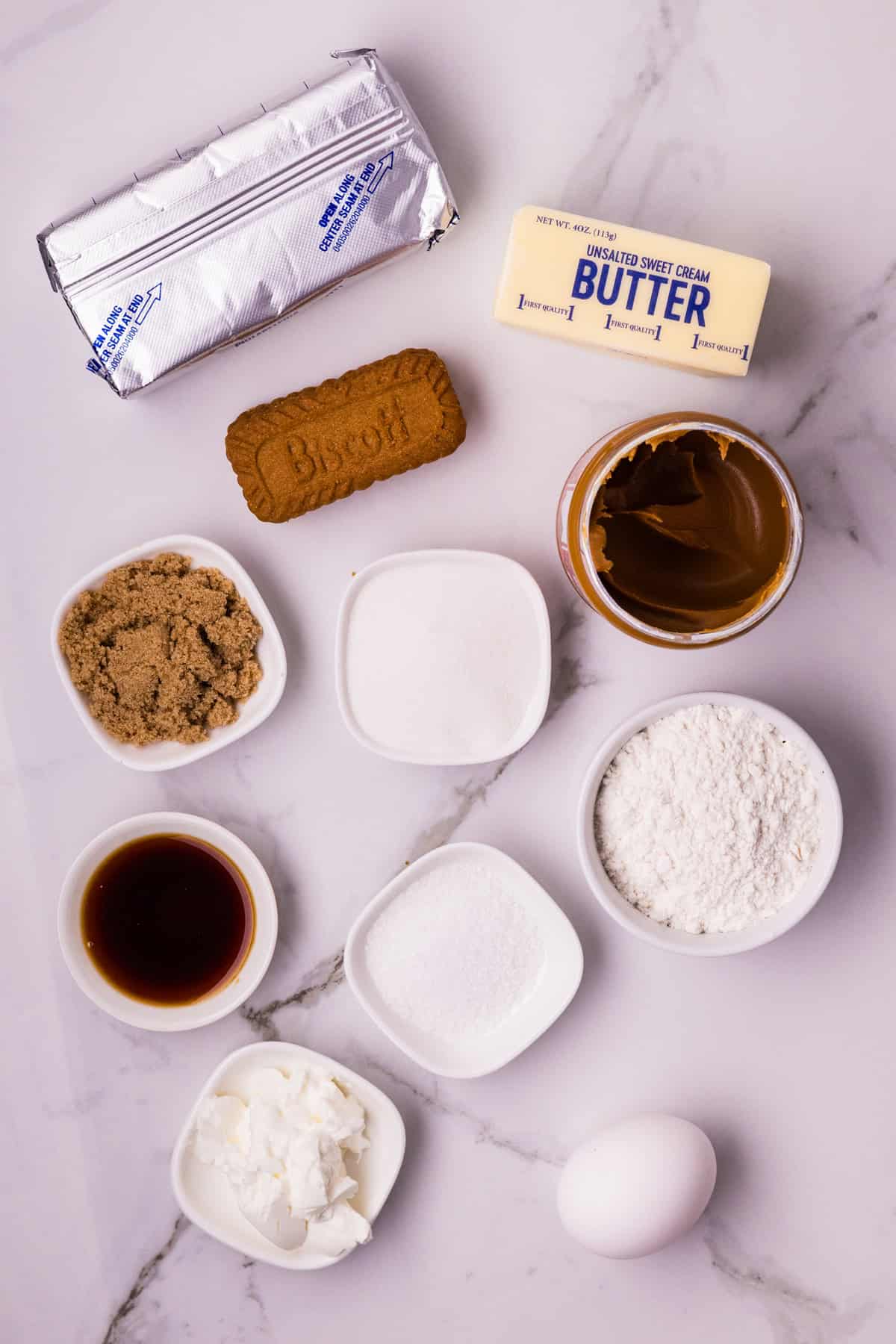 A creamy cookie butter cheesecake filling is baked in a Biscoff crust and topped with more cookie butter in this Biscoff Cheesecake recipe. Overhead view of ingredients needed to make Biscoff cheesecake