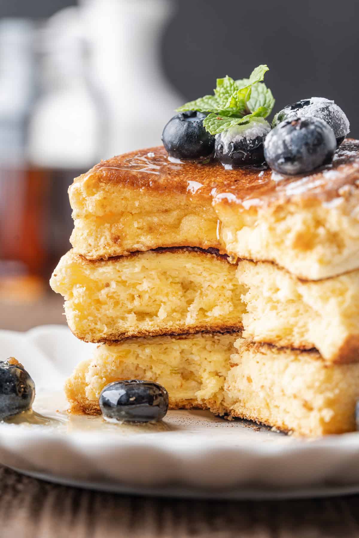 These Japanese Soufflé Pancakes are tall, fluffy, jiggly, and unbelievably soft, thanks to the meringue in the batter. A stack of Japanese souffle pancakes with a bite missing