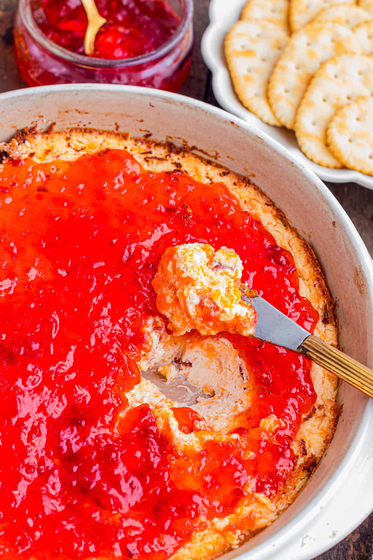 This easy Pepper Jelly Cream Cheese Dip is creamy, cheesy, smoky, and perfectly sweet and spicy! Perfect for holidays & game days. A knife scooping up some pepper jelly cream cheese dip