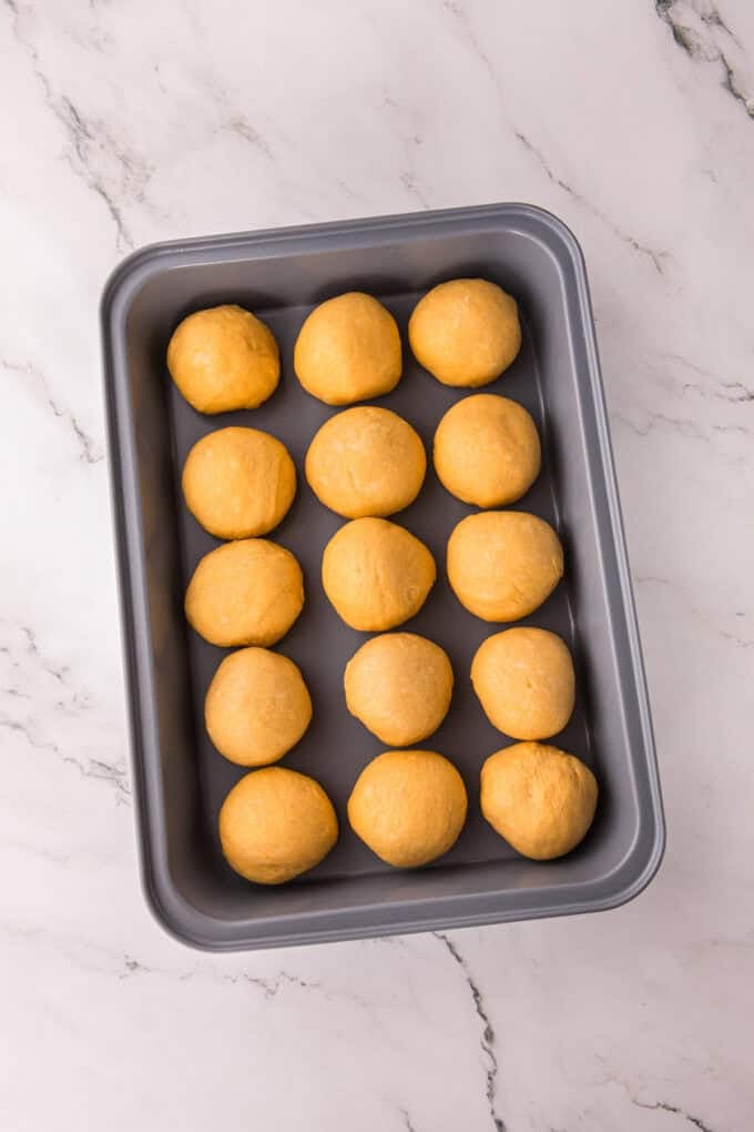 These soft, fluffy Sweet Potato Rolls are brushed with warm honey butter right out of the oven. Easy to make with a few basic ingredients! Balls of sweet potato roll dough before rising