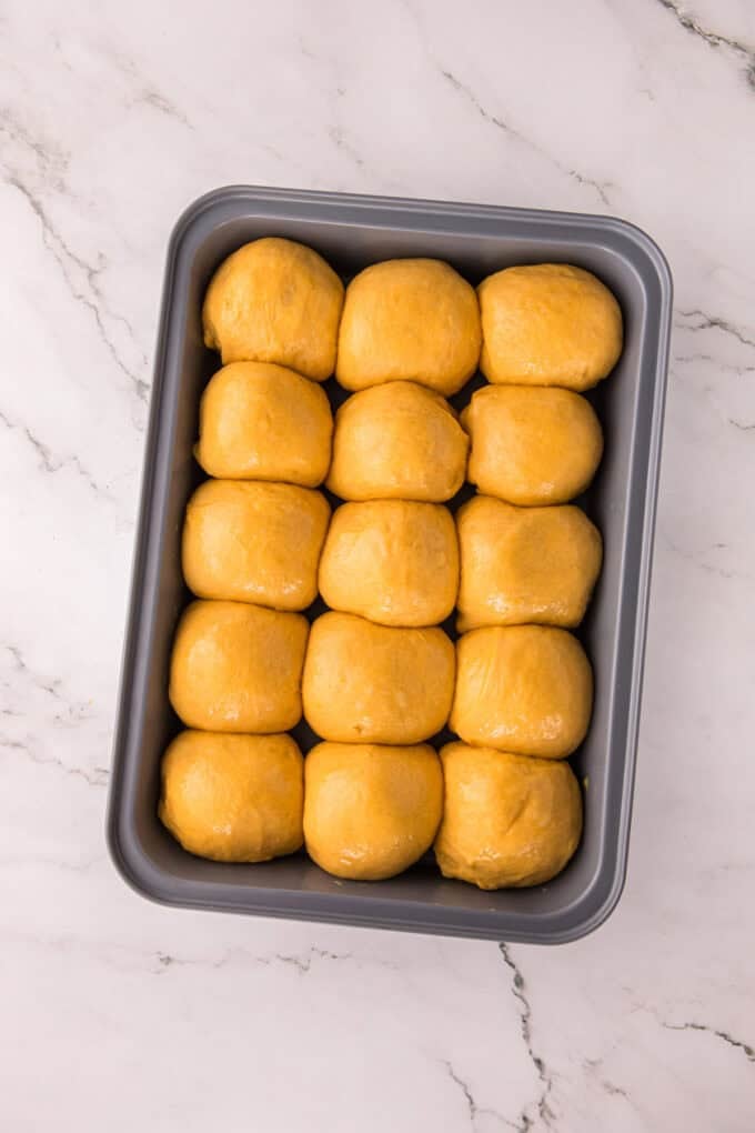 These soft, fluffy Sweet Potato Rolls are brushed with warm honey butter right out of the oven. Easy to make with a few basic ingredients! Balls of sweet potato roll dough after rising
