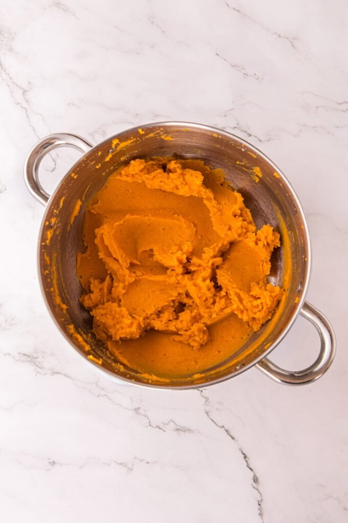 These soft, fluffy Sweet Potato Rolls are brushed with warm honey butter right out of the oven. Easy to make with a few basic ingredients! Mashed sweet potatoes in a pot