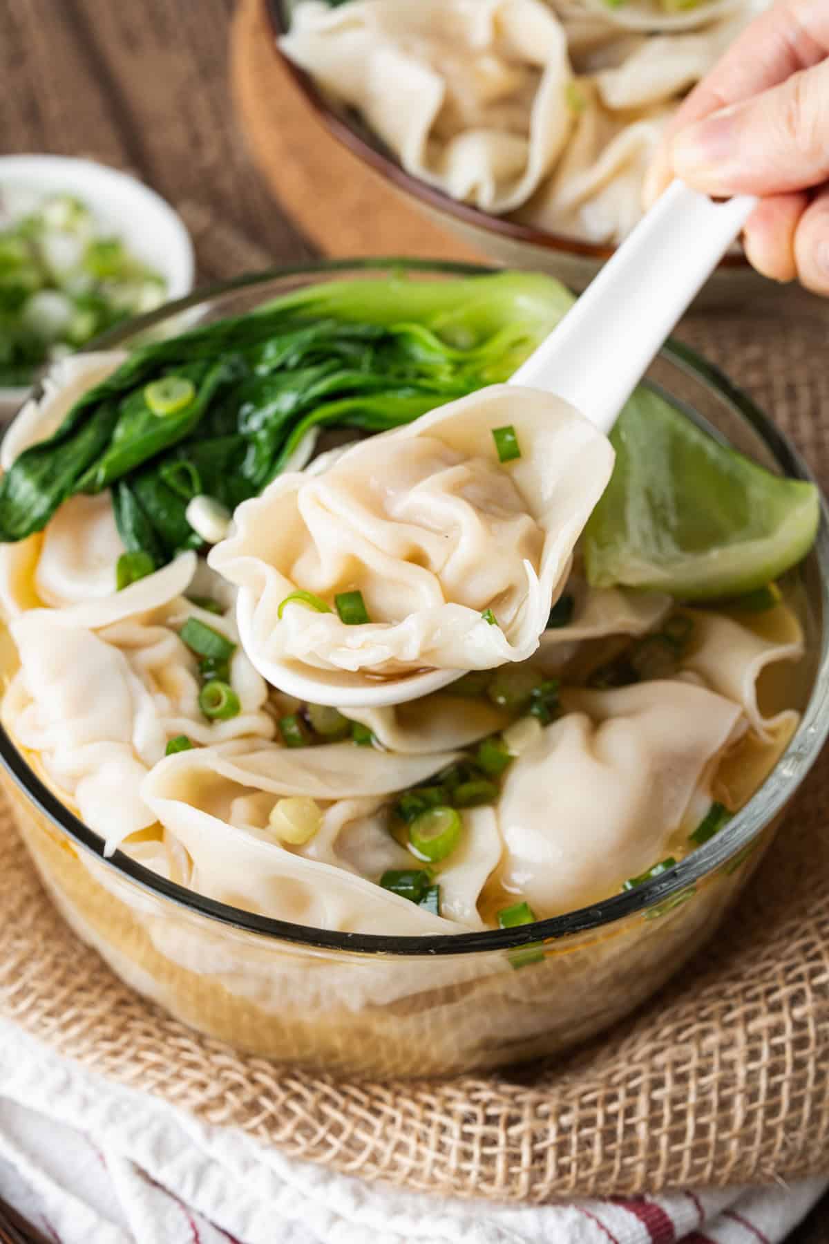 This easy Wonton Soup features tender homemade wontons filled with juicy pork and shrimp in a light, aromatic chicken broth. A spoon above a glass bowl of wonton soup