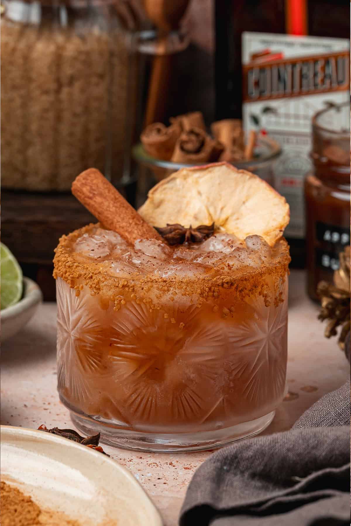 This Apple Butter Margarita is a delicious fall cocktail made with apple butter, tequila, orange liqueur, and fresh lime juice. Apple Butter Margarita in a glass with a cinnamon stick and sliced apple.