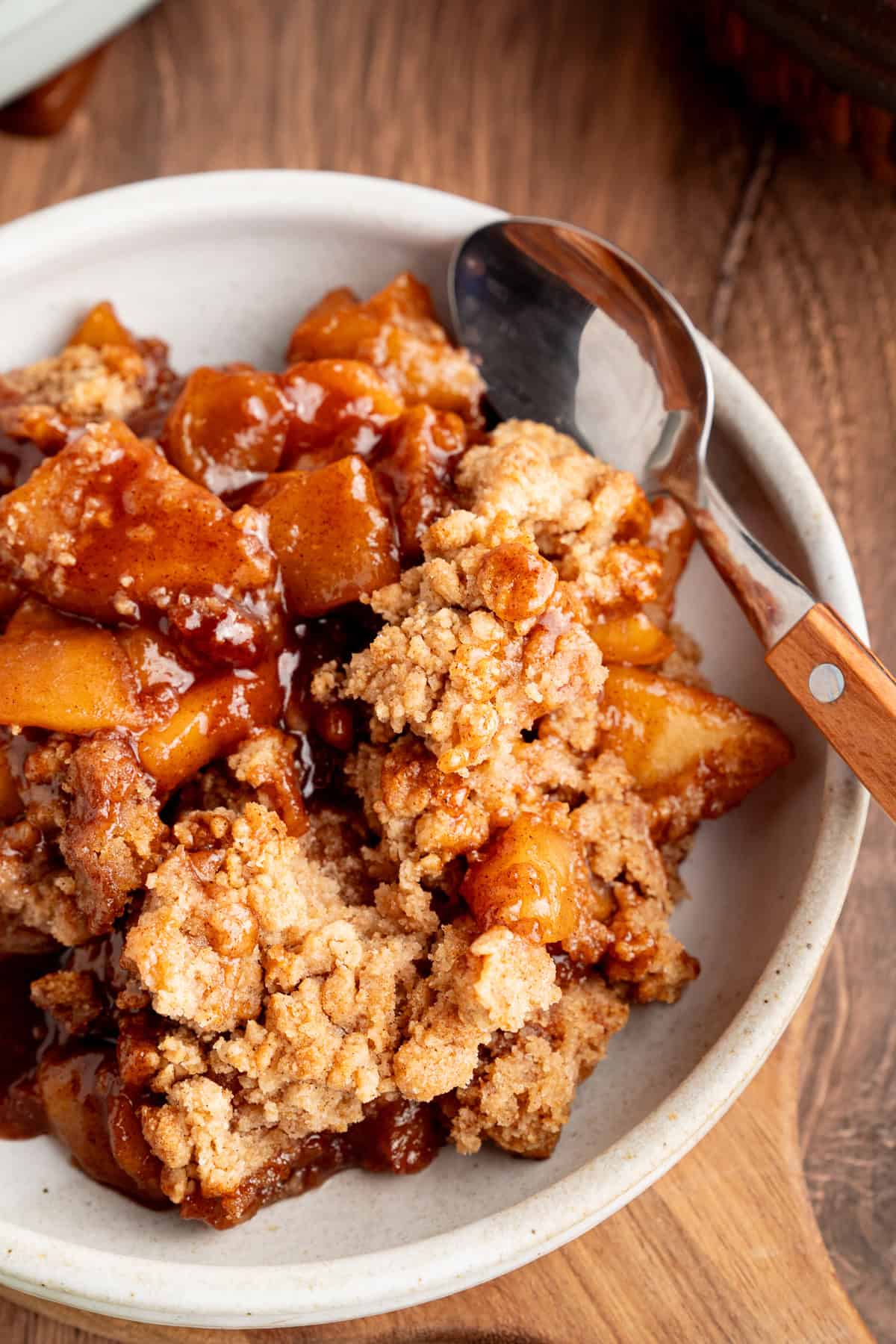 Tender spiced apple filling is topped with a snickerdoodle batter to make this irresistible Apple Cobbler recipe. A bowl of apple cobbler with a spoon