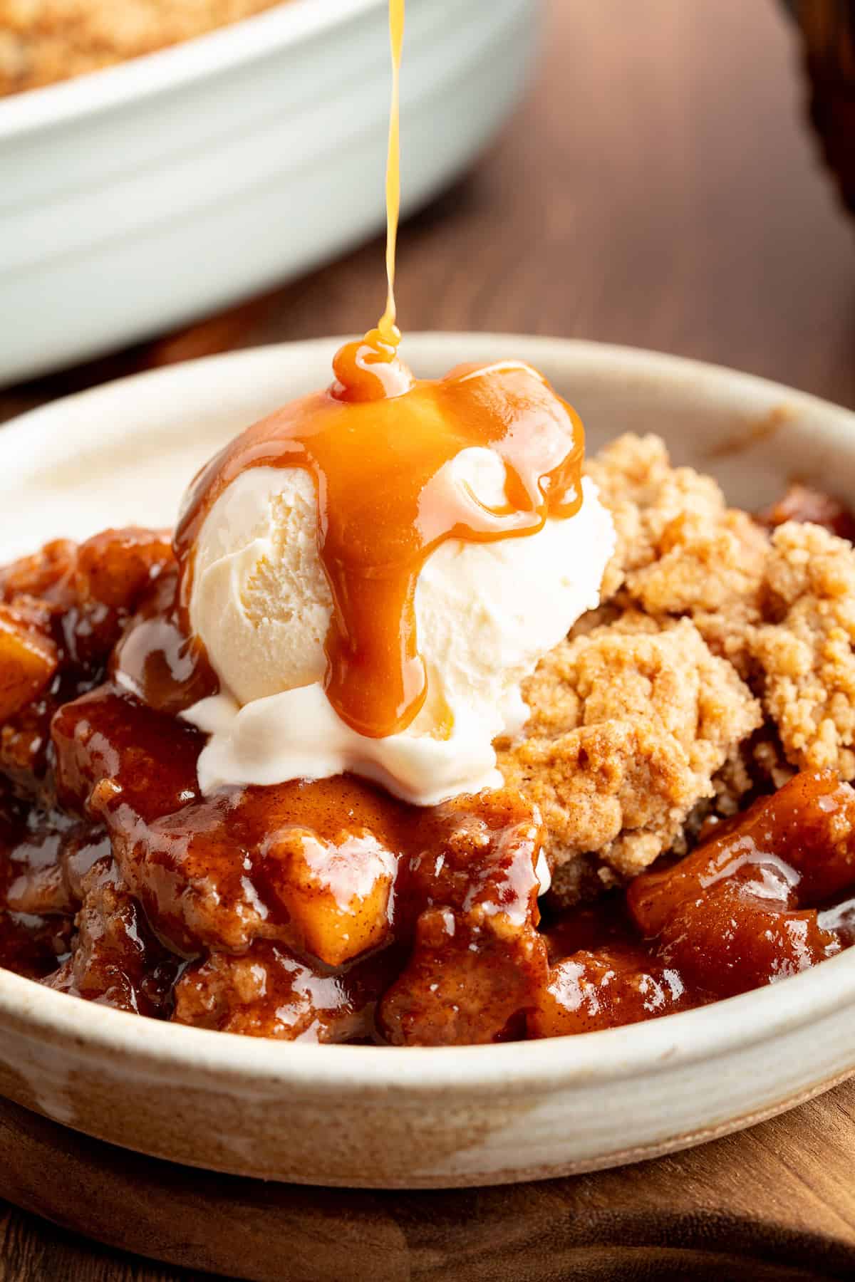 Drizzling caramel sauce over ice cream on apple cobbler