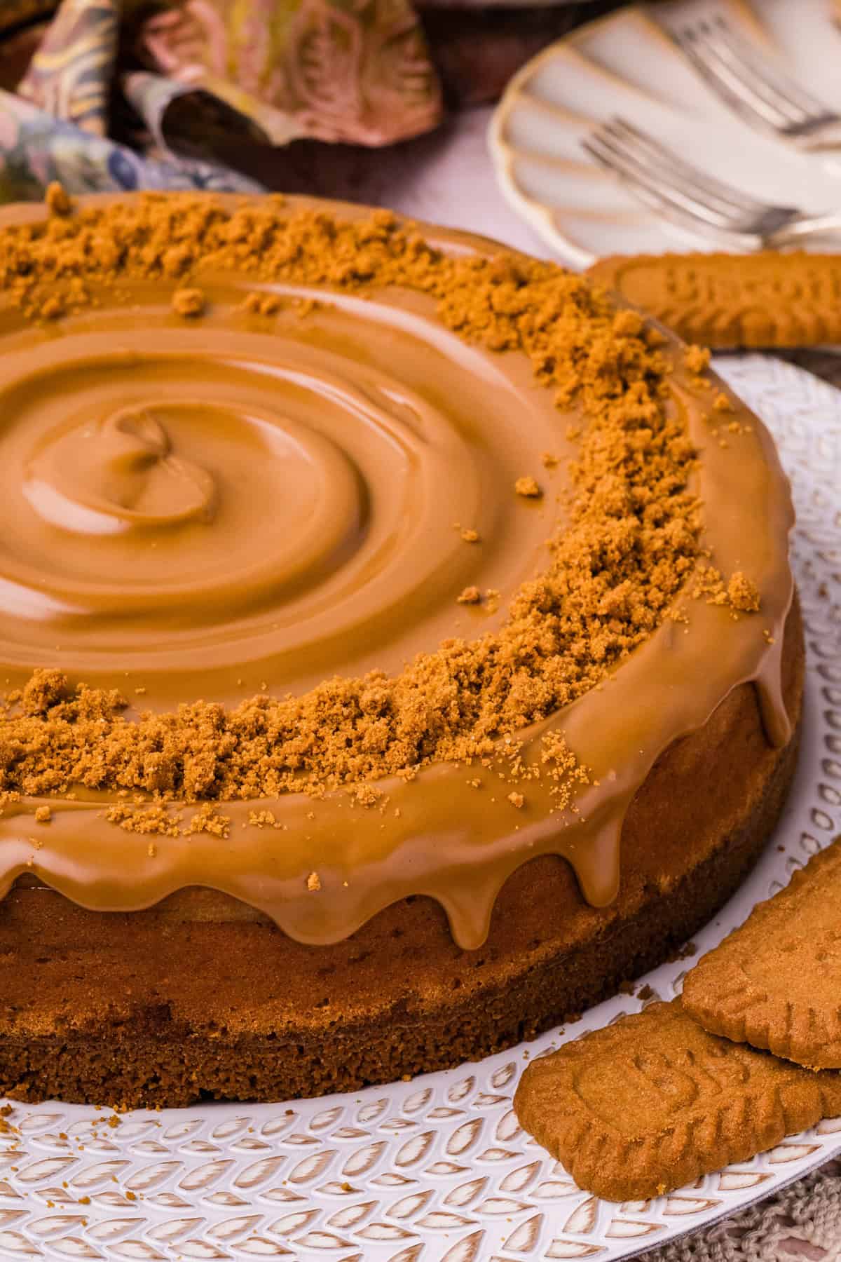 A creamy cookie butter cheesecake filling is baked in a Biscoff crust and topped with more cookie butter in this Biscoff Cheesecake recipe. baked Biscoff cheesecake on a platter.